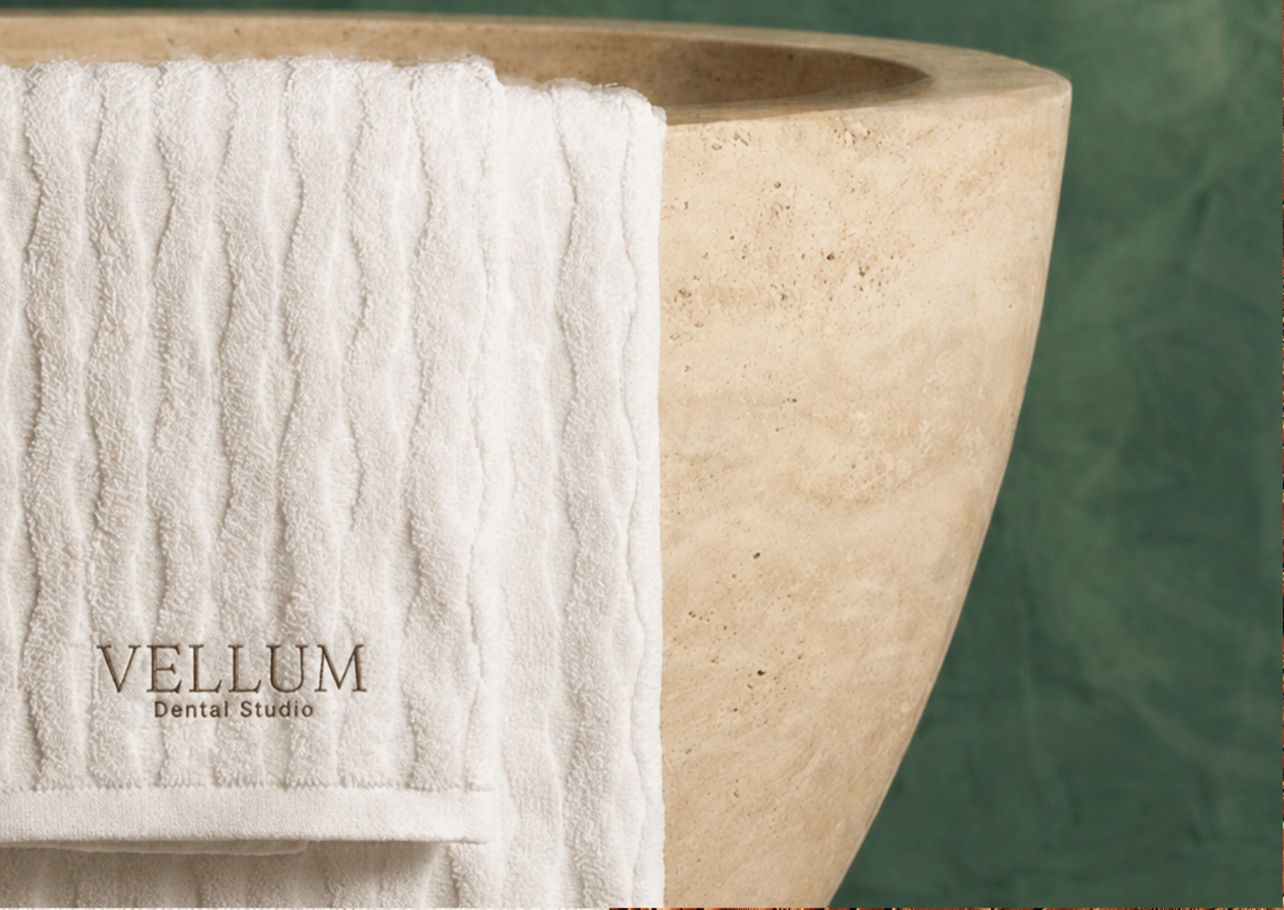 Vellum branded towel draped over a travertine basin